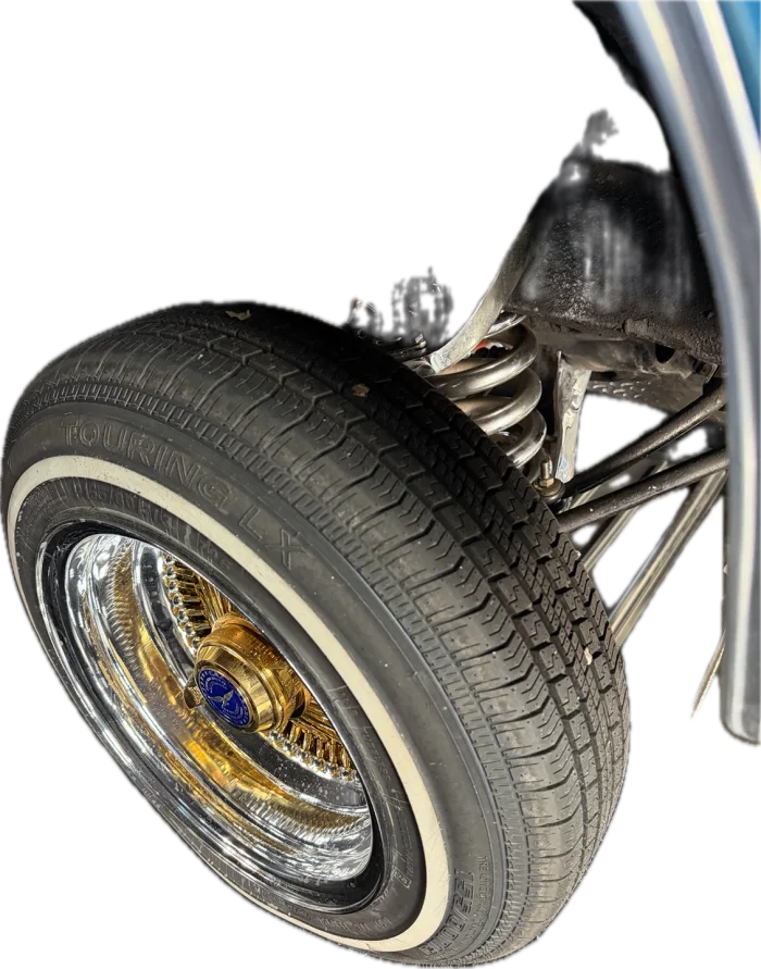 Gold and chrome wire wheel with a whitewall on one of the shop's Impalas